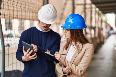 Mand and woman architects using touchpad write on report at street
