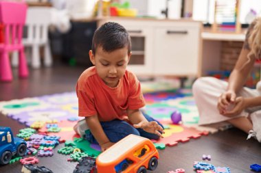 Anaokulunda ciddi bir ifadeyle oturan sevimli İspanyol çocuk.