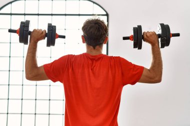 Spor merkezinde dambıllar kullanan Latin kökenli genç bir adam.