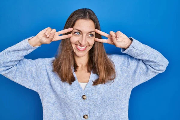 Young Woman Standing Blue Background Doing Peace Symbol Fingers Face — Stockfoto