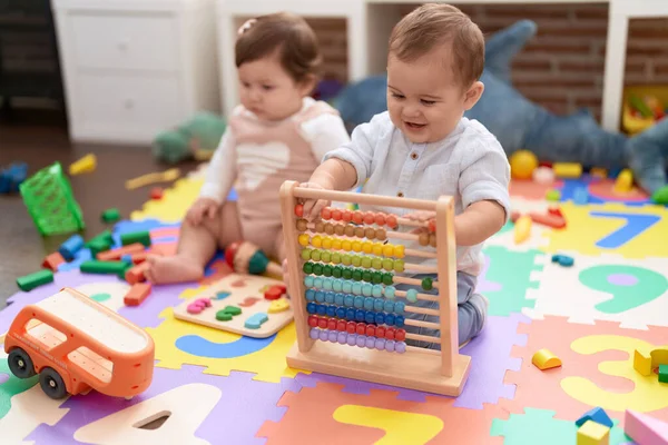 stock image Two toddlers playing with abacus sitting on floor at kindergarten