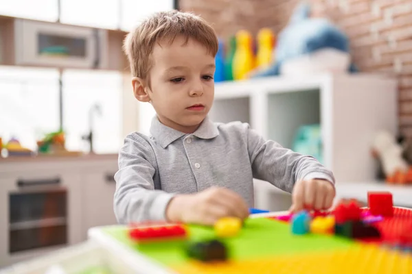 stock image Adorable toddler playing with construction blocks sitting on table at kindergarten