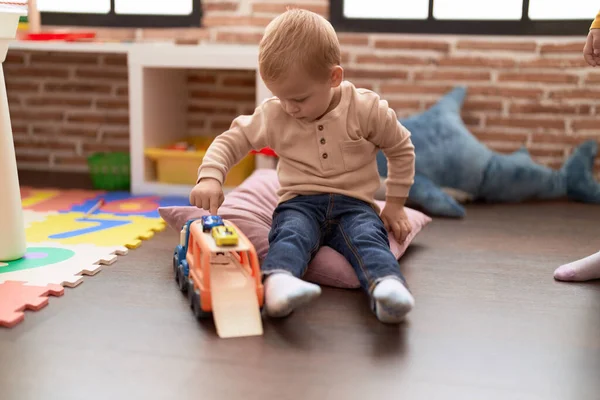 幼稚園で床に座っている車のおもちゃで遊ぶ愛らしい幼児 — ストック写真