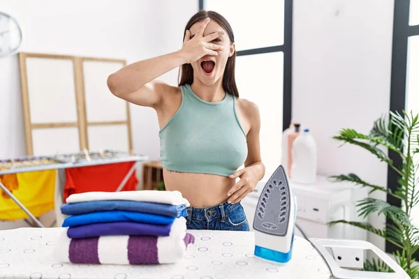 Young Hispanic Woman Ironing Clothes Laundry Room Peeking Shock Covering — Fotografia de Stock