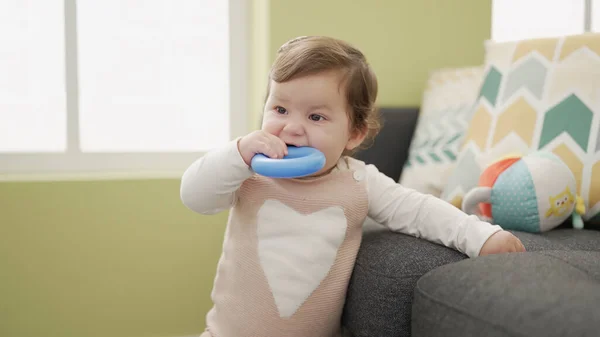 Adorable toddler bitting plastic hoop standing at home