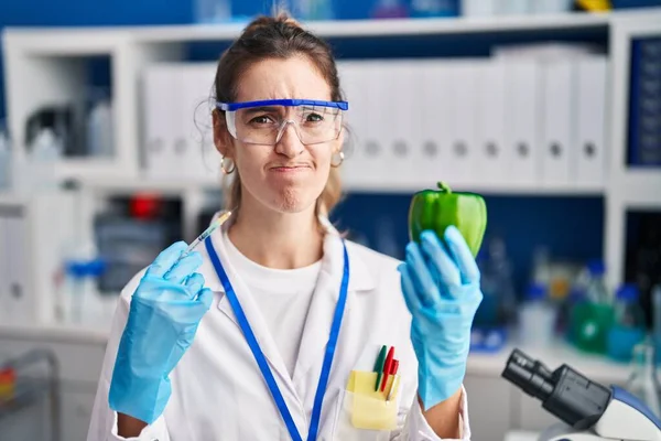 在科学家实验室工作的年轻的惊慌失措的女人 对蔬菜持怀疑和紧张的态度 因为问题而皱着眉头 消极的人 — 图库照片