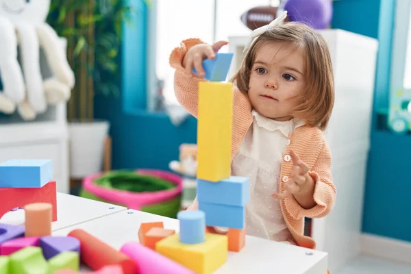 stock image Adorable blonde toddler playing with construction blocks standing at kindergarten