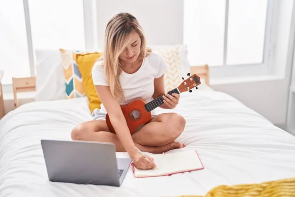 Young Blonde Woman Having Online Ukulele Lesson Composing Song Bedroom — Stockfoto