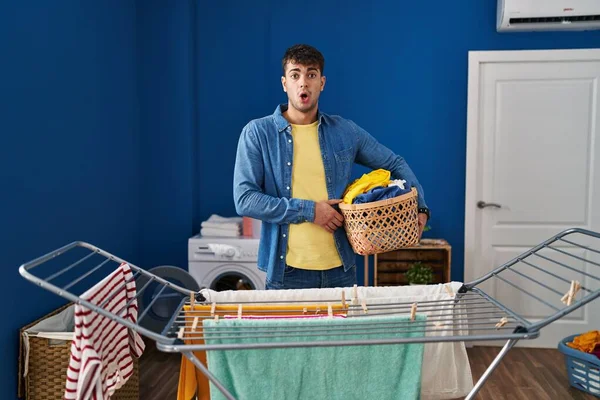 Young Hispanic Man Hanging Clothes Clothesline Scared Amazed Open Mouth — Stock Photo, Image