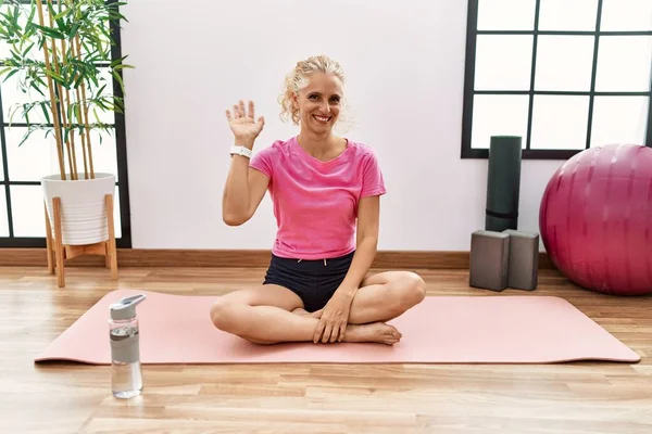 Middle Age Blonde Woman Sitting Yoga Mat Waiving Saying Hello — Stock Photo, Image