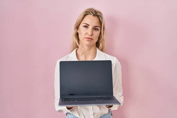 Young Caucasian Woman Holding Laptop Showing Screen Relaxed Serious Expression — Zdjęcie stockowe