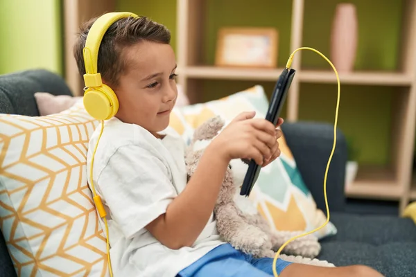 Adorable Niño Hispano Usando Touchpad Auriculares Sentados Sofá Casa —  Fotos de Stock