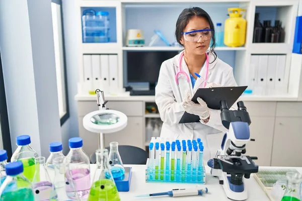 研究室で文書に科学者の制服を着た若い中国人女性 — ストック写真