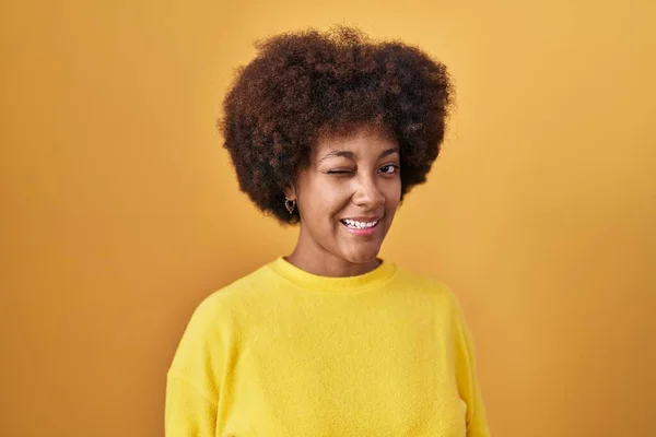 Young African American Woman Standing Yellow Background Winking Looking Camera — Stockfoto