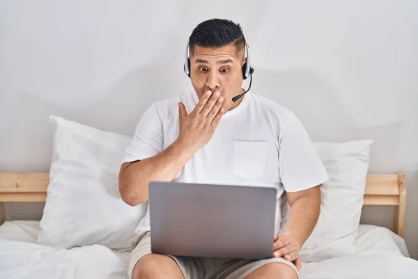 Hispanic Young Man Using Computer Laptop Bed Covering Mouth Hand — Stok fotoğraf