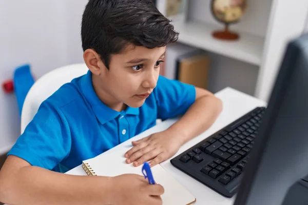 在课堂上用电脑在笔记本上写字的惊慌失措的男孩是可敬的 — 图库照片