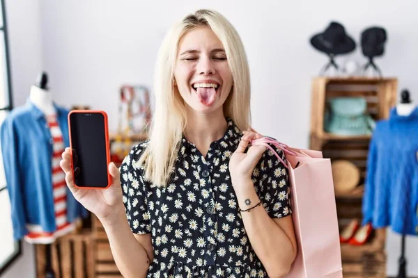 Young Blonde Woman Holding Shopping Bags Showing Smartphone Screen Sticking —  Fotos de Stock