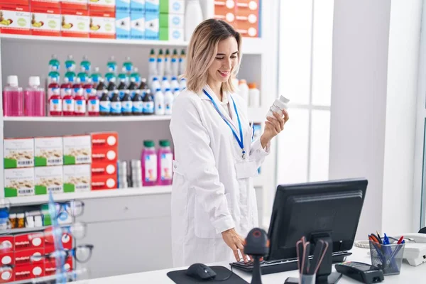 Young Woman Pharmacist Using Computer Holding Pills Bottle Pharmacy — Foto de Stock