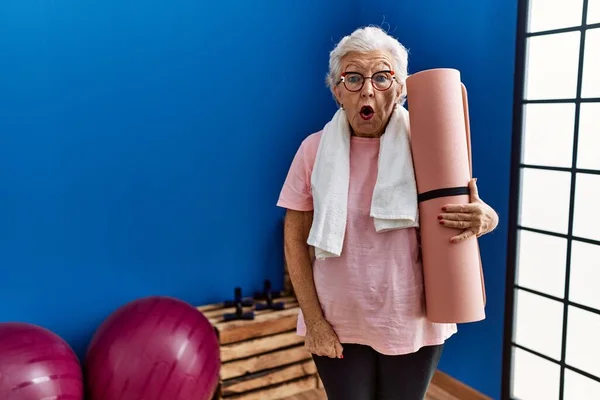 Oudere Vrouw Met Grijs Haar Houdt Yoga Mat Bang Verbaasd — Stockfoto