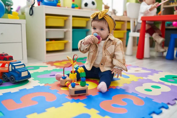 幼稚园里可爱的金发碧眼的幼儿坐在地板上吸吮玩具 — 图库照片