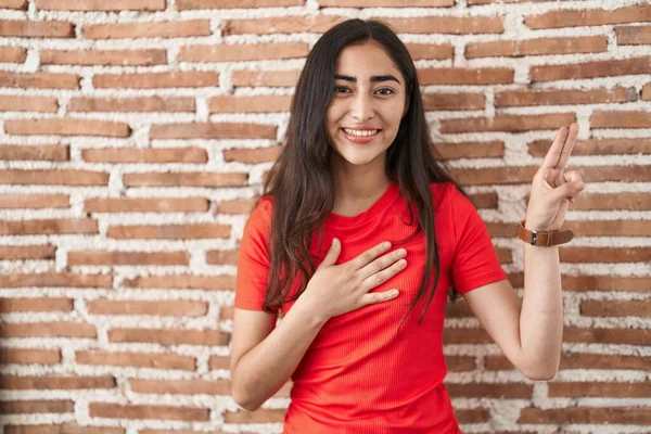 Young Teenager Girl Standing Bricks Wall Smiling Swearing Hand Chest — Stockfoto