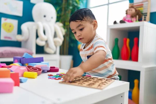 令人羡慕的是 他的惊慌失措的幼儿站在幼儿园里玩数学拼图游戏 — 图库照片