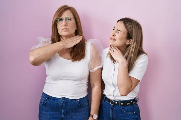 Hispanic mother and daughter wearing casual white t shirt over pink background cutting throat with hand as knife, threaten aggression with furious violence