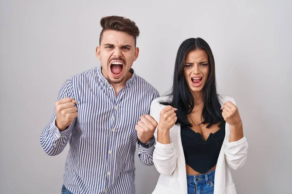 Young Hispanic Couple Standing White Background Angry Mad Raising Fists — Photo