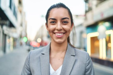Genç ve güzel İspanyol kadın yönetici gülümseyerek caddede duruyor.