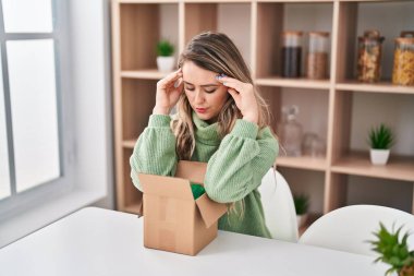 Evde endişeli bir ifadeyle boks paketi açan genç bir kadın.