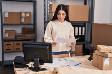 Young beautiful hispanic woman ecommerce business worker reading document at office