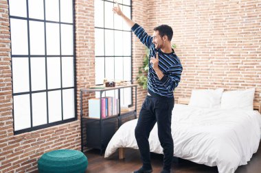 Young hispanic man smiling confident dancing at bedroom