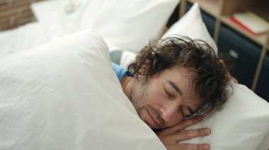 Genç İspanyol adam yatakta uzanıp yatak odasında uyuyor.