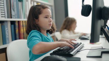 Two kids students using computer studying at classroom
