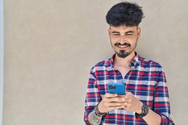Young hispanic man smiling confident using smartphone over white isolated background