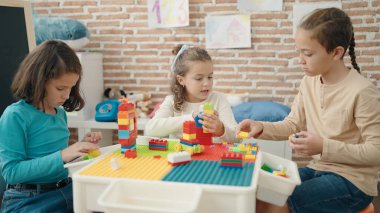 Group of kids playing with construction blocks sitting on table at kindergarten