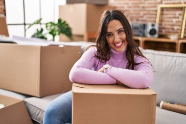 Young hispanic woman smiling confident leaning on package at new house