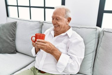 Son sınıf öğrencisi evdeki kanepede oturup kahve içiyor.