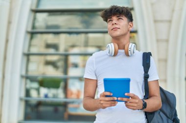 Latin kökenli genç bir öğrenci üniversitede rahat bir ifadeyle dokunmatik ped kullanıyor.