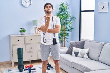Handsome latin man wearing sportswear at home looking at the camera blowing a kiss with hand on air being lovely and sexy. love expression. 