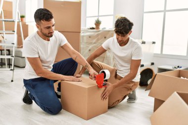 İki İspanyol erkek gülümsüyor. Yeni evlerinde kendilerine güvenen karton kutuları var.