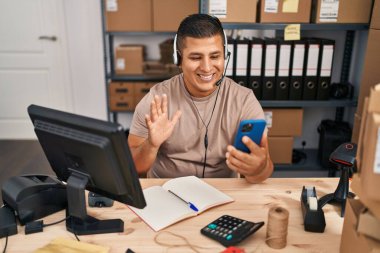 İspanyol genç adam küçük işletme ekommerce çalışan video çağrı olumlu ve mutlu görünüyor ayakta ve gülümseyerek dişlerini gösteren bir gülümseme ile 