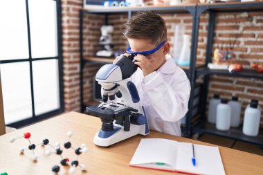 Laboratuvar sınıfında mikroskop kullanan sevimli İspanyol çocuk.