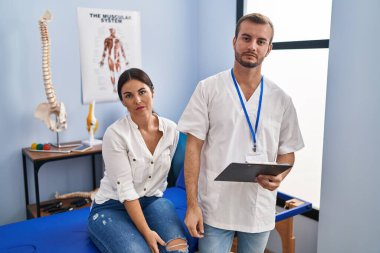 Young hispanic woman at physiotherapist appointment relaxed with serious expression on face. simple and natural looking at the camera. 