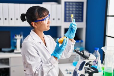 Laboratuvarda limon ve test tüpü tutan genç ve güzel İspanyol bilim kadını.