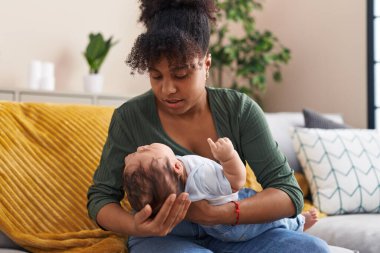 Mother and son hugging each other sitting on sofa at home