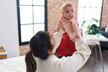 Mother and daughter smiling confident sitting on bed at bedroom