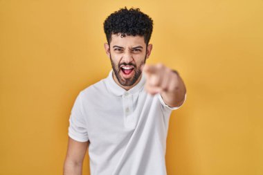 Arab man standing over yellow background pointing displeased and frustrated to the camera, angry and furious with you 