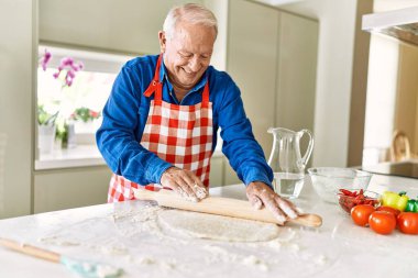 Son sınıf öğrencisi, mutfakta pizza hamuru saklarken kendinden emin gülümsüyor.