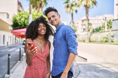 Man and woman couple smiling confident using smartphone at street